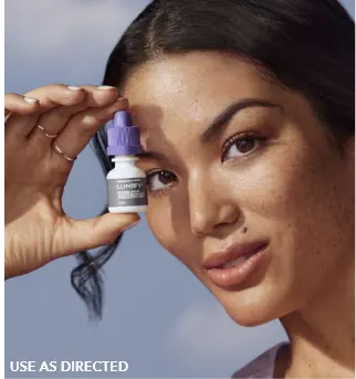 Woman holding a Lumify redness relieving eye drops bottle