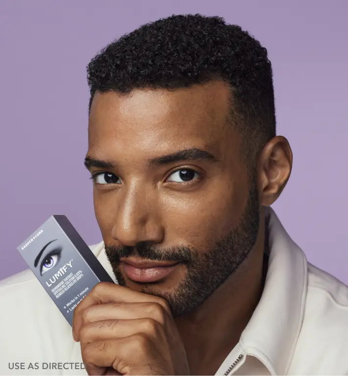 Close up of a man holding Lumify redness relieving eye drops box