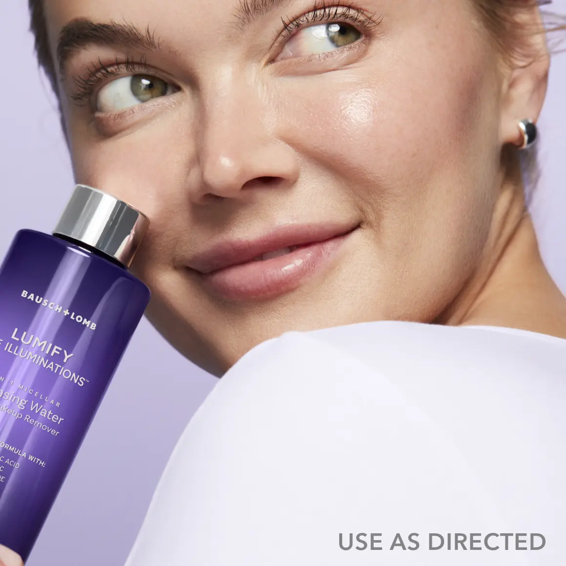 Close up of a woman looking over her shoulder holding a bottle of Lumify cleansing water