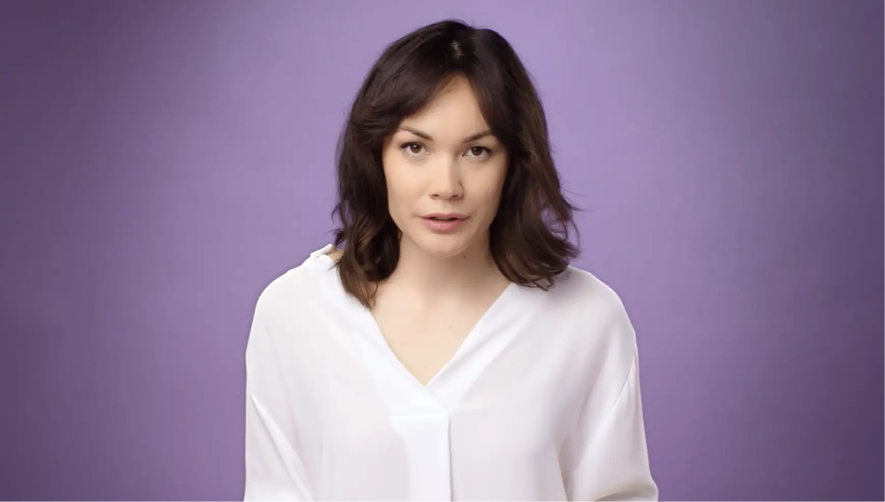 Woman with brown hair wearing a white shirt
