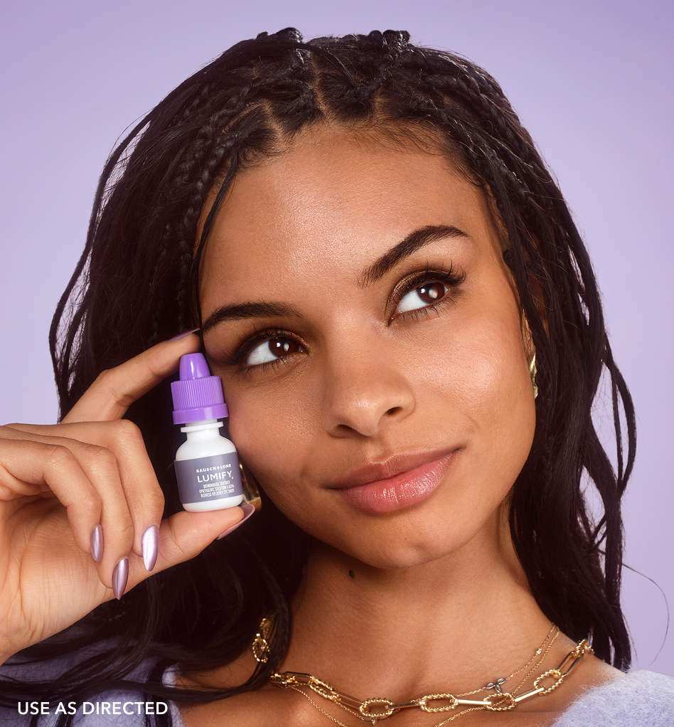 Woman holding a Lumify redness relieving eye drops bottle