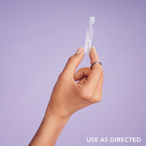 Close up of a woman looking over her shoulder holding a bottle of Lumify cleansing water